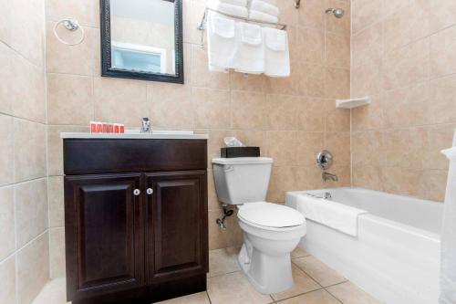 a bathroom with a toilet and a tub and a sink at Econo Lodge in Sudbury