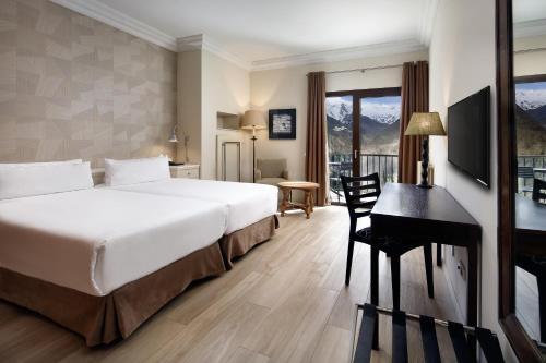 a hotel room with a large bed and a desk at Parador de Vielha Spa & Wellness in Vielha