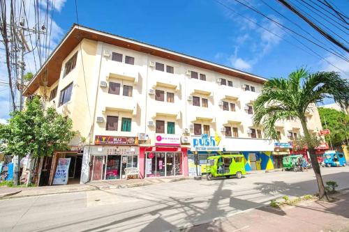 a building on a street with a yellow van parked in front at Palette Boracay Isle by The White Beach in Boracay