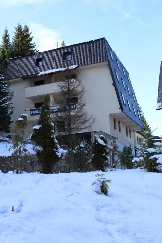 a large building in the snow with trees in front at Apartmani Čolić Vlašić in Vlasic