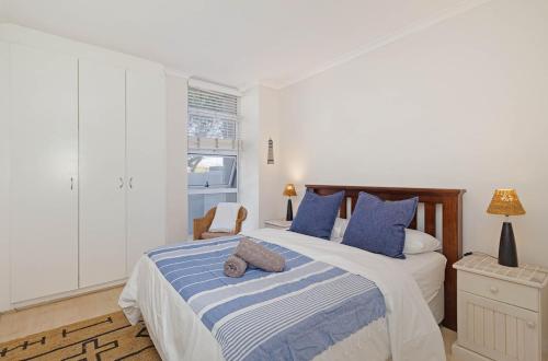 a bedroom with a large bed with blue pillows at The Sands Cottage in Cape Town