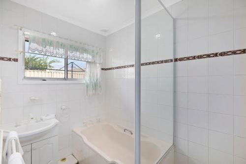 a white bathroom with a tub and a sink at Fravent house in Toukley