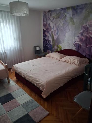 a bedroom with a large bed with a floral wall at Apartment Upper Town in Gospić