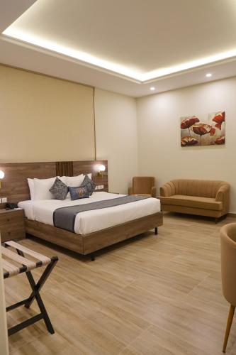a bedroom with a large bed and a couch at RT Serene Hotel - Larkana in Lāhori