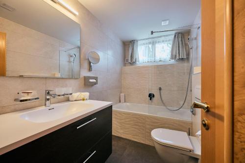 a bathroom with a sink and a toilet and a tub at Pension Regina in Lech am Arlberg