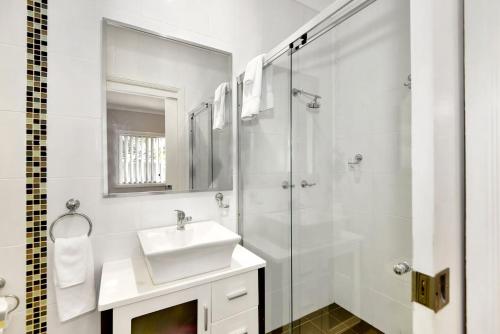a white bathroom with a sink and a shower at The Gallipoli Residence in Long Jetty