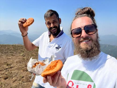 two men holding food in their hands on a hill at COORG CLlMATE FARM HOUSE in Madikeri