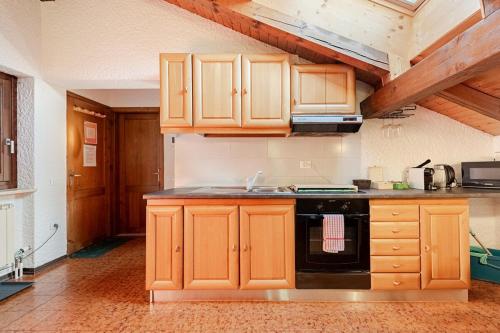 a kitchen with wooden cabinets and a black stove at Val di Sole Apartment in Monclassico