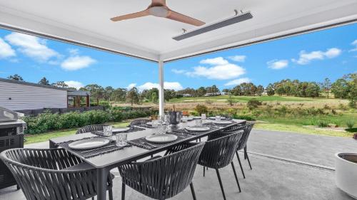 a dining table and chairs on a patio with a large window at 21 Forever in Pokolbin