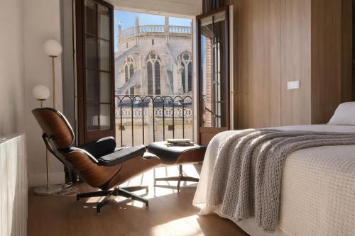 a bedroom with a bed and a chair and a window at Acariciando la Catedral by apartamentoscatedralcamino in Burgos