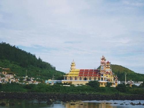 a building with a red roof next to a river at Khánh Sạn Trang Thư in Ly Son