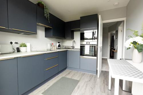 a kitchen with blue cabinets and a white table at WOODFIELD ROAD - Two bed in Harrogate with cosy living room fire. in Harrogate