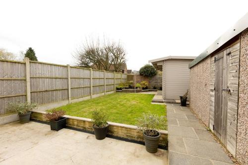 a backyard with a fence and a yard with potted plants at WOODFIELD ROAD - Two bed in Harrogate with cosy living room fire. in Harrogate