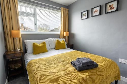 a bedroom with a bed with yellow pillows and a window at WOODFIELD ROAD - Two bed in Harrogate with cosy living room fire. in Harrogate