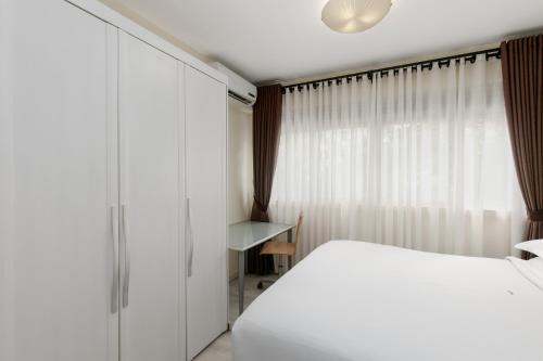 a bedroom with a white bed and a window at Constellation Apartments in Kampala