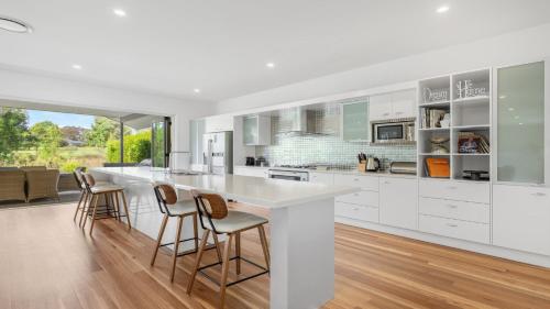 a kitchen with white cabinets and bar stools at Dashaz Dream - The Vintage in Pokolbin