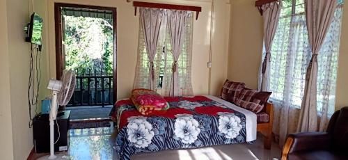 a bedroom with a bed and a balcony with windows at Streamside Guest House in Mawlynnong