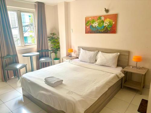a bedroom with a large white bed with two chairs at Liva in Ho Chi Minh City