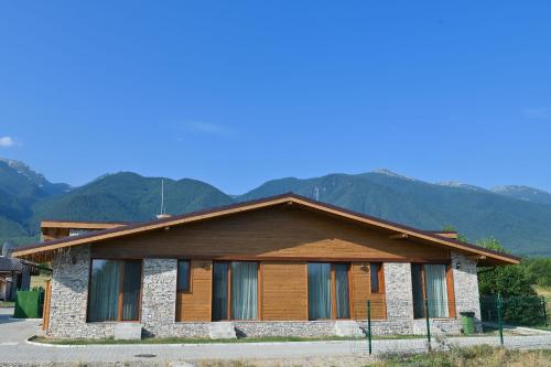 a house with mountains in the background at Villa Raphael w Jacuzzi near Pirin Golf Resort in Bansko