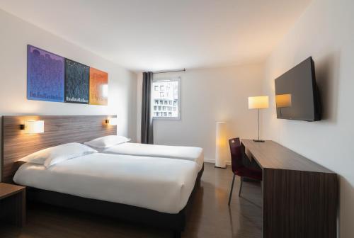 a hotel room with a large bed and a desk at The Originals Residence Appart Hôtel Hévéa Valence in Valence