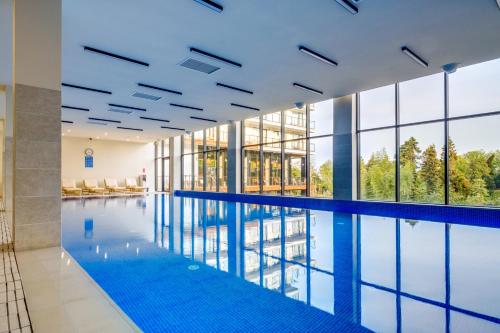 a swimming pool in a building with glass windows at Greenwood Hotel Restaurant & Spa in Batumi