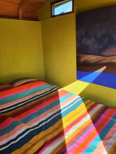 a bedroom with a colorful bed with a window at De Maanloper in Bant