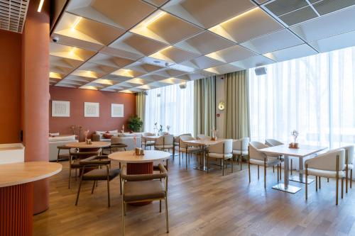 a restaurant with tables and chairs in a room at Renion Almaty Hotel in Almaty