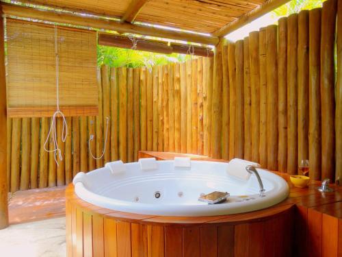 a bath tub in a room with a wooden wall at Casa Morada dos Pássaros - 3 suítes in Imbassai