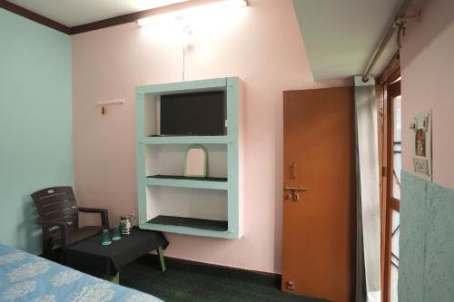 a room with a bed and a tv on a wall at Sangam View Homestay Devprayag in Devaprayāg