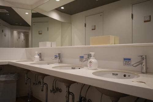 a bathroom with three sinks and a large mirror at Santiago Guesthouse Kyoto in Kyoto
