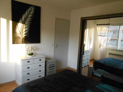 sypialnia z łóżkiem, komodą i lustrem w obiekcie Appartement Marco Polo w mieście Mandelieu-la-Napoule