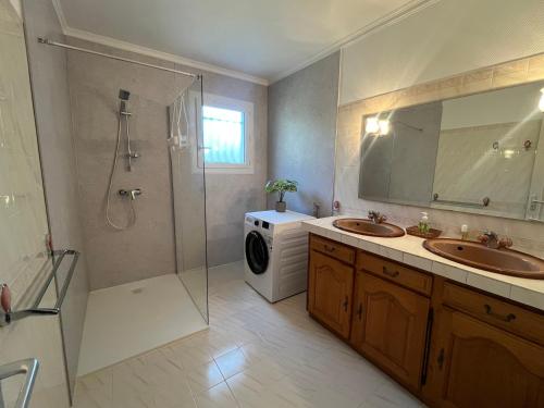 a bathroom with two sinks and a shower and a washing machine at Aux 4 Saisons in Tabre