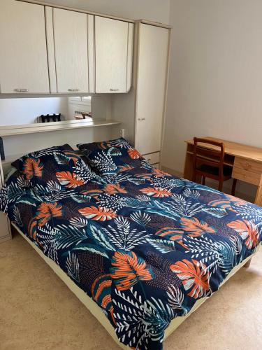 a bedroom with a bed with a blue and orange blanket at Aux 4 Saisons in Tabre