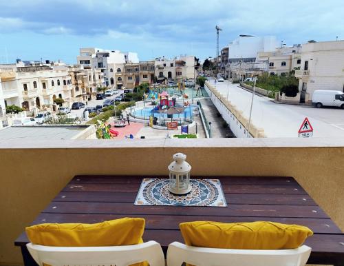 a table on a balcony with a view of a city at Joseph 2, Charming Retreat with park views and close to the airport in Siġġiewi
