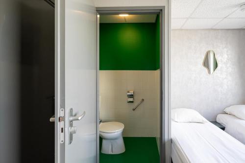 a bathroom with a toilet and a green wall at Strandhotel Wemeldinge in Wemeldinge