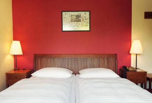 two beds in a room with a red wall at Romantik Hotel Kaufmannshof in Bergen auf Rügen