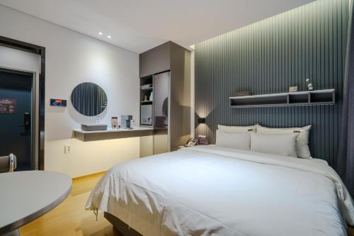 a bedroom with a large white bed and a table at Hotel Hariu in Gwangju