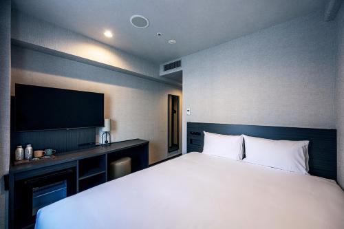 a bedroom with a large bed and a television at THE KNOT FUKUOKA Tenjin in Fukuoka