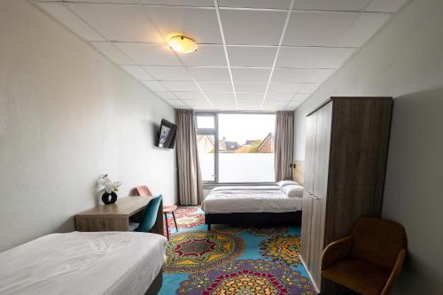 a hotel room with two beds and a window at Strandhotel Wemeldinge in Wemeldinge