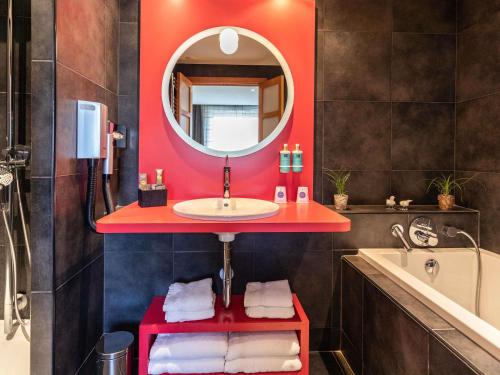 a bathroom with a sink and a mirror and a tub at Novotel Valence Sud in Valence