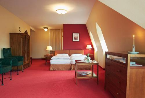 Habitación de hotel con cama y alfombra roja en Romantik Hotel Kaufmannshof en Bergen auf Rügen