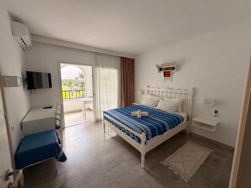 a bedroom with a bed and a tv and a balcony at Résidence Neffati in Hammamet