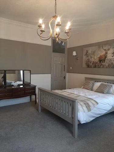 a bedroom with a large bed and a chandelier at Stonehouse Apartment in Mexborough