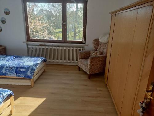 a bedroom with a bed and a chair and a window at Unterkunft Mau in Rotenburg an der Wümme