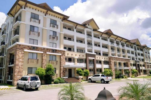 a large white building with two cars parked in a parking lot at One Oasis Condo beside SM Mall in Davao City
