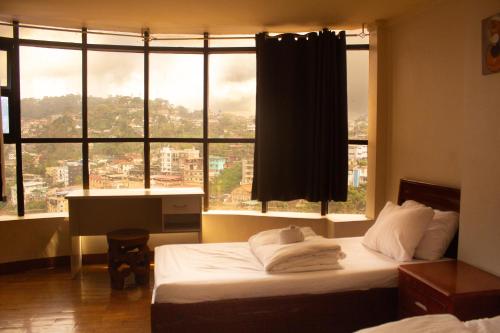 a bedroom with two beds and a large window at Zhongkebole Suites in Baguio