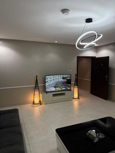 a living room with a flat screen tv and two lights at Manazil Al Joud -AlSafa منازل الجود - الصفا in Jeddah