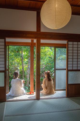 three women sitting in a room looking out the window at Lucia Seaside Villa Amami in Amami