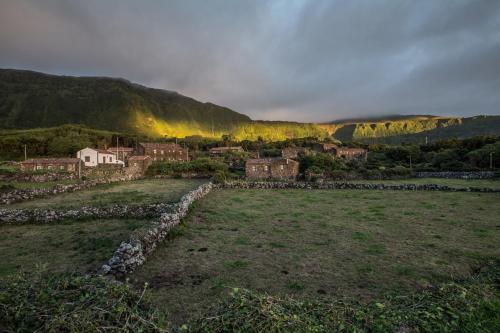 a village in a field with a stone wall at Aldeia da Cuada in Faja Grande