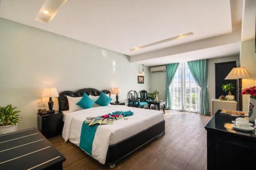 a bedroom with a large bed with blue pillows at The Sunriver Boutique Hotel Hue in Hue